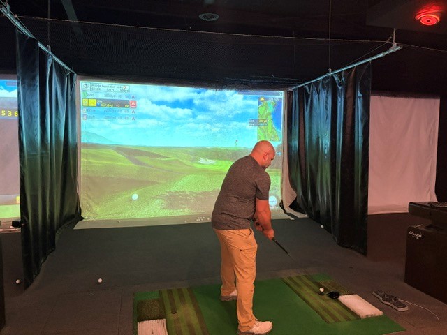 Dudes playing indoor golf at Coastal Swing